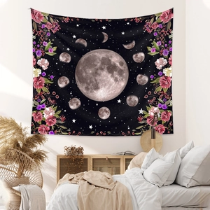 Detail of bohemian moon phase tapestry with red roses hanging in a minimalist bedroom