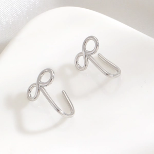Détail de boucles d'oreilles infinity argentées sur soie blanche et brillant