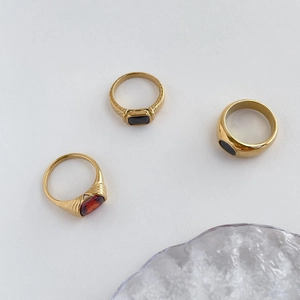 Close-up of vintage gold rings featuring ruby and black gemstones on a gray background