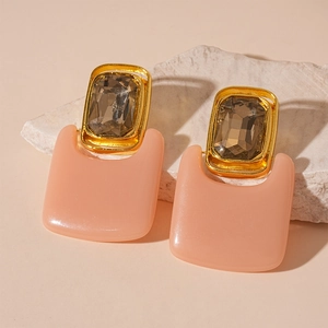 Detail view of vintage geometric drop earrings with gold frames and peach resin charms