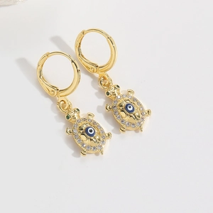 Macro shot of golden turtle earrings featuring blue evil eye accents and white zircons