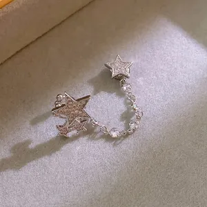 Silver star earrings with magnetic clip and zirconia tassels on gray display base