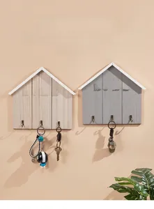 Detail of wooden house-shaped wall hooks with HOME letters and three vintage metal pegs