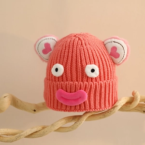 Gros plan du bonnet tricoté rose vif avec texture épaisse et visage de dessin animé