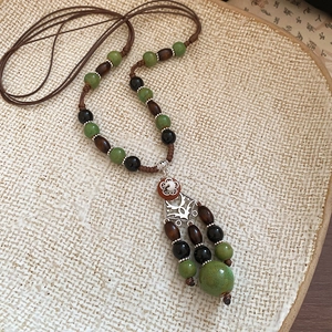 Detail of ethnic beaded necklace with brown coconut shells and silver pendant on ceramic tray