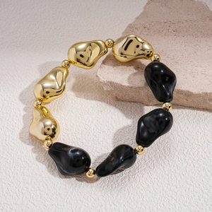 Gros plan d'un bracelet en perles acryliques géométriques aux textures dorées et marbrées
