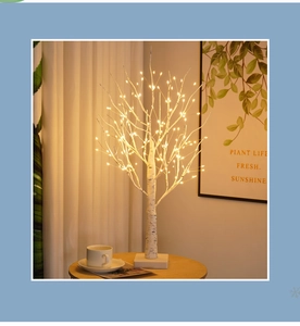 Detail of LED birch tree lamp with warm light and white branches for indoor festive decor