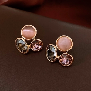 Macro detail of gold flower earrings with pink cat eye stone and smoky purple gems