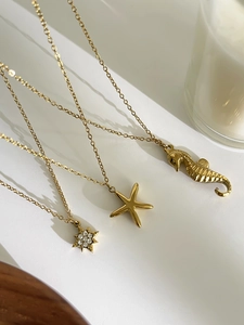 Détail de colliers dorés avec étoile de mer et hippocampe sur un fond de style de vie pur