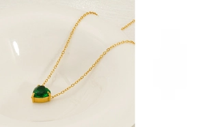 Detailed macro view of heart-shaped green zircon pendant on a fine gold chain necklace