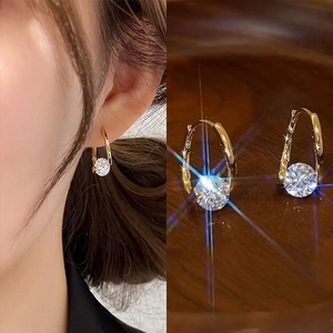 Detail of gold U-shaped earrings featuring round cubic zirconia in a split-view display