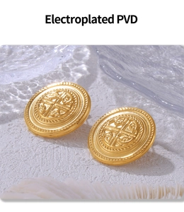 Close-up of gold-plated circular stud earrings with intricate embossed crest design