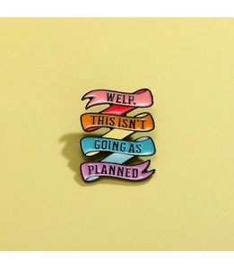 Macro shot of colorful enamel rainbow ribbon brooch with motivational English text