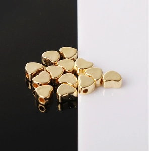 Macro-opname van gouden hartvormige kralen voor DIY-sieraden op reflecterend oppervlak