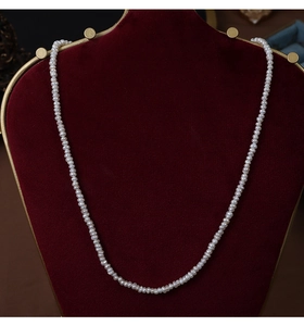 Macro shot of small white freshwater pearls displayed on a red velvet jewelry stand