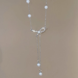 Detail view of silver Y-necklace with pearls and a sparkling diamond-set bow pendant