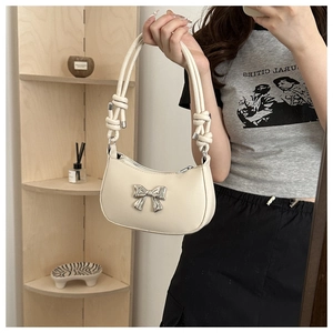 Close-up of cream bow-knot shoulder bag featuring silver metal buckle and knotted strap