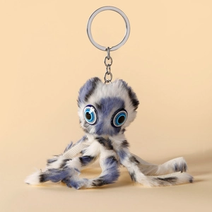 Porte-clés poulpe en peluche à pois bleus et blancs avec anneau métal sur fond beige