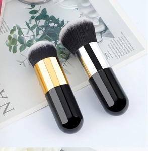 Close-up of dual-tone round foundation and blush brushes with black handles on white background