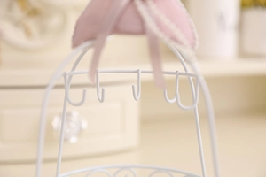 Detail of white metal jewelry stand hooks with elegant pink ribbon and fabric decor