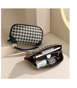 Classic houndstooth clutch bag detail with zipper closure and spacious interior storage