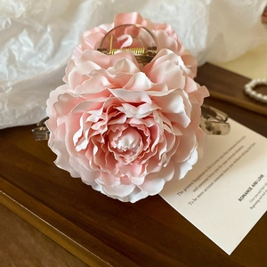 Detail view of pink rose flower hair claw clip with golden spring on wooden tray