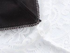 Gros plan détaillé sur la robe en similicuir noir avec ourlet en dentelle blanche et coutures