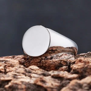 Macro shot of a polished silver stainless steel signet ring on a dark rustic wood bark