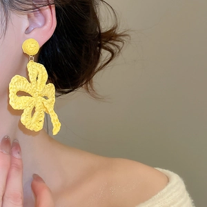 Close-up of yellow handmade raffia woven four-leaf clover flower earrings on model