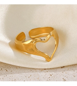 Macro detail of a golden heart-shaped open ring resting on soft white silk fabric