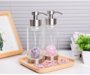 Detail view of two glass lotion dispensers with colorful crystal stones inside the base