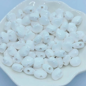 Macro shot of white shell-shaped ceramic beads for DIY jewelry making in a white plate