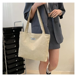 Detailed shot of beige corduroy tote bag showing fashion tag and durable texture