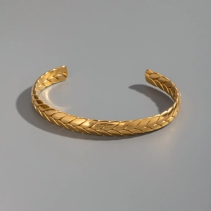 Dettaglio macro del bracciale rigido minimalista in oro 18K con trama a spiga