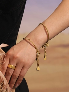 Detail von vergoldeten Edelstahl-Armbändern mit Sternanhängern und einem strukturierten Ring
