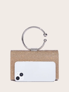 Detail of a gold rhinestone clutch bag with ring handle and a phone for size comparison