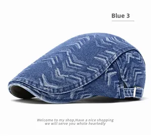 Close-up of washed blue denim beret featuring white geometric patterns and metal adjustment buckle
