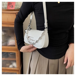 Detail of white textured leather half-moon bag with silver chain and adjustable strap