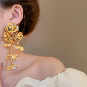 Detailed view of yellow chiffon rose tassel earrings worn by a model in warm light