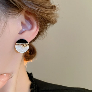 Gros plan d'une mannequin portant des boucles d'oreilles rondes en résine vintage