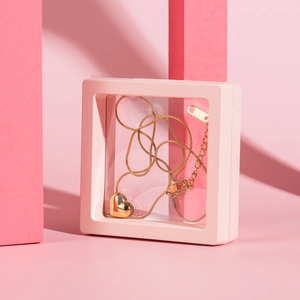 Polished gold 3D heart pendant necklace displayed in a pink floating jewelry storage box