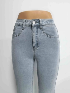 Detail of high waist flare jeans showing metal button, zipper fly and denim texture