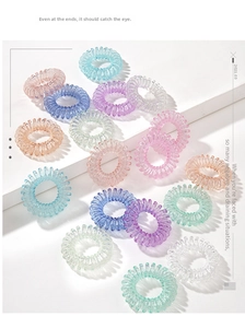 Macro detail of multi-colored spiral telephone wire hair ties on minimalist white steps