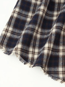 Detail of plaid fabric texture with frayed edges and fringe on a checkered maxi dress