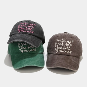 Detail of embroidered inspirational text and floral design on washed cotton baseball caps