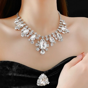 Exquisite close-up of a silver-tone necklace and brooch set with sparkling teardrop crystals