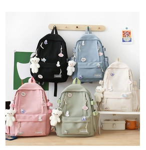 Dettaglio di zaini color pastello in cinque colori con ciondoli e orsetto di peluche