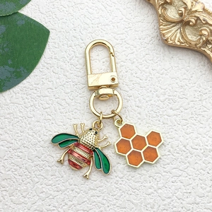 Detail of bee and honeycomb keychain with gold alloy finish and colorful enamel accents
