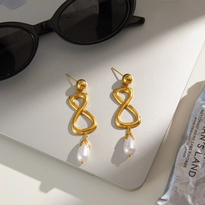 Boucles d'oreilles pendantes infini dorées avec perles blanches sur un ordinateur