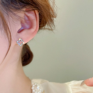 Close-up of model wearing a diamond-encrusted hollow four-leaf clover stud earring